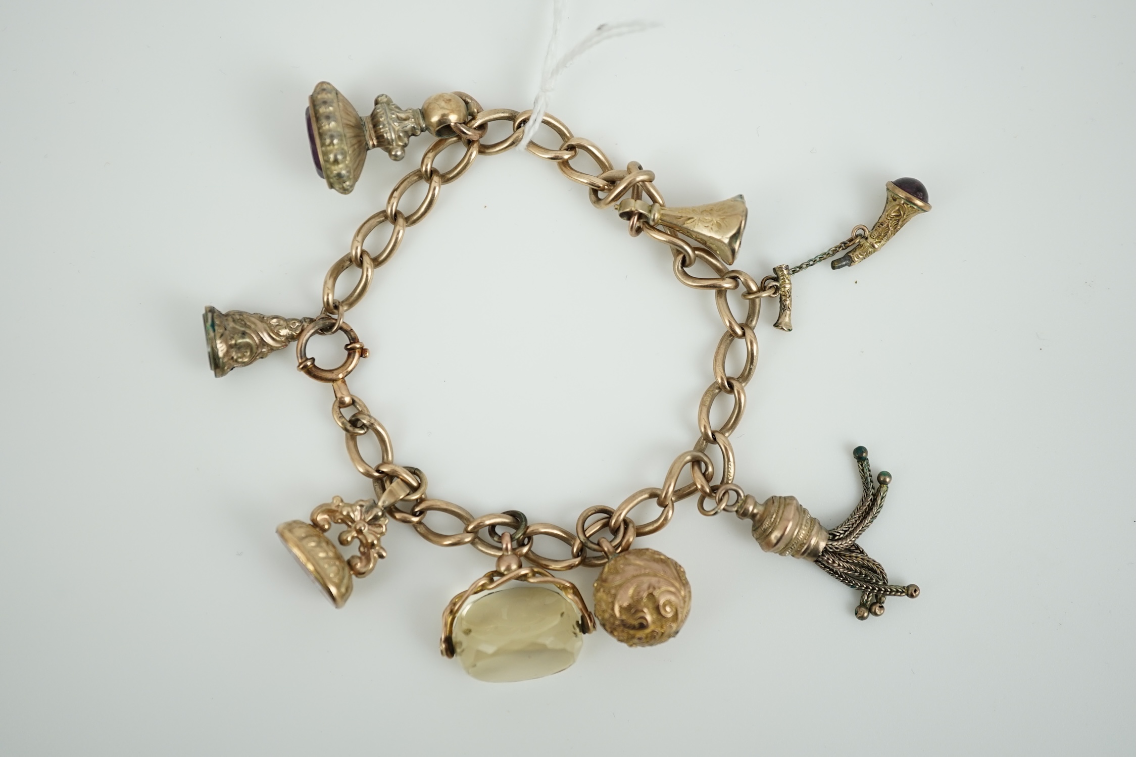 A 9ct gold charm bracelet, hung with eight assorted yellow metal overlaid charms, gross weight 33.4 grams.